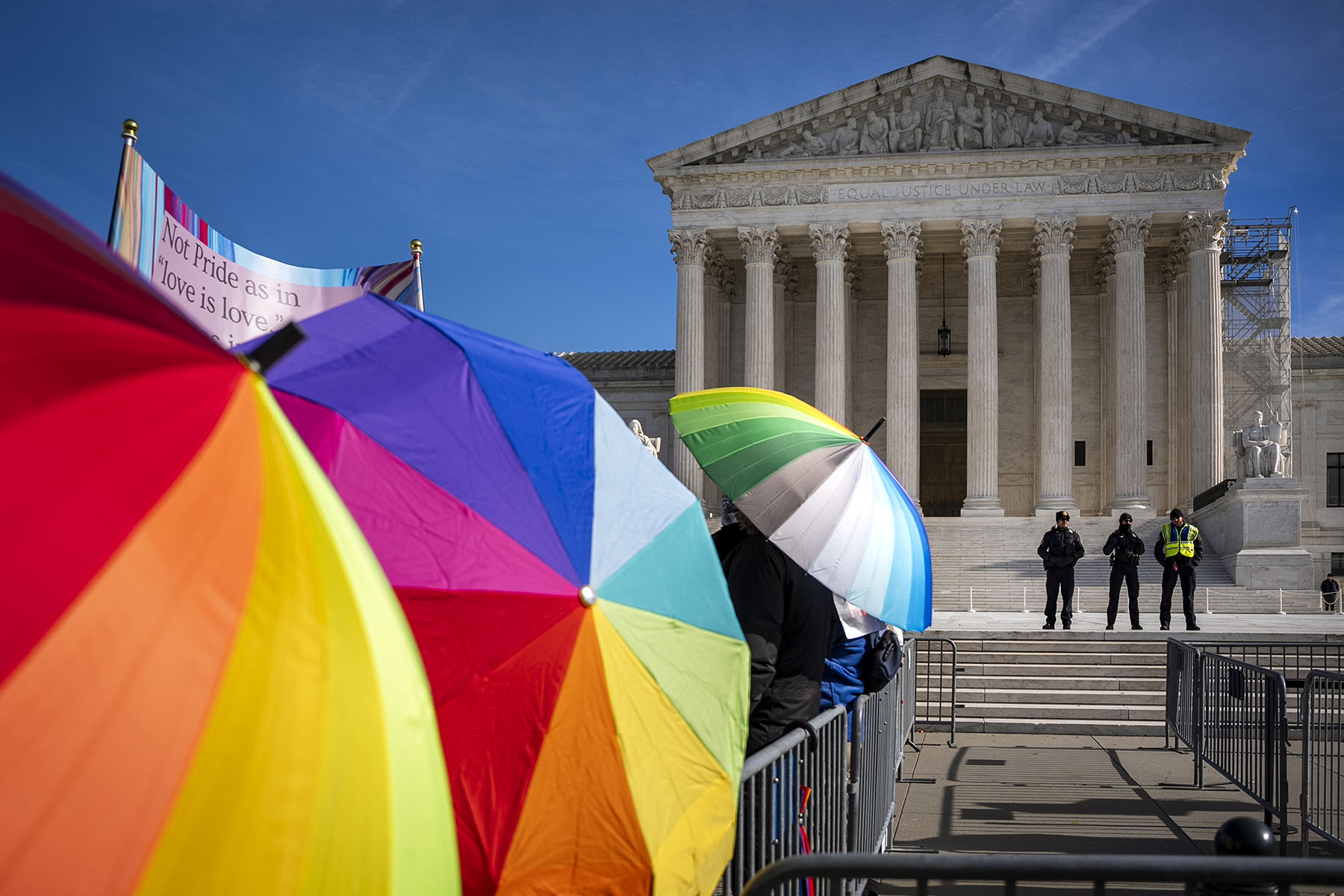 People with rainbow umbrellas protest in support of care for transgender youth outside the Supreme Court during the United States v. Skrmetti arguments.