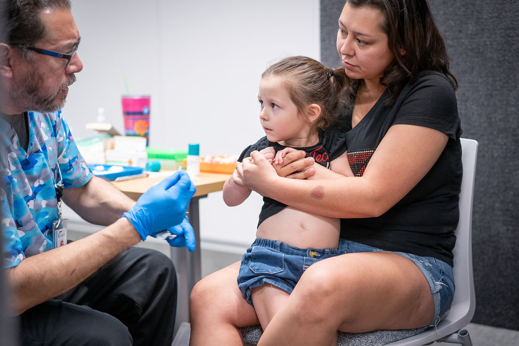 A mother holds her child while she gets vaccinated.