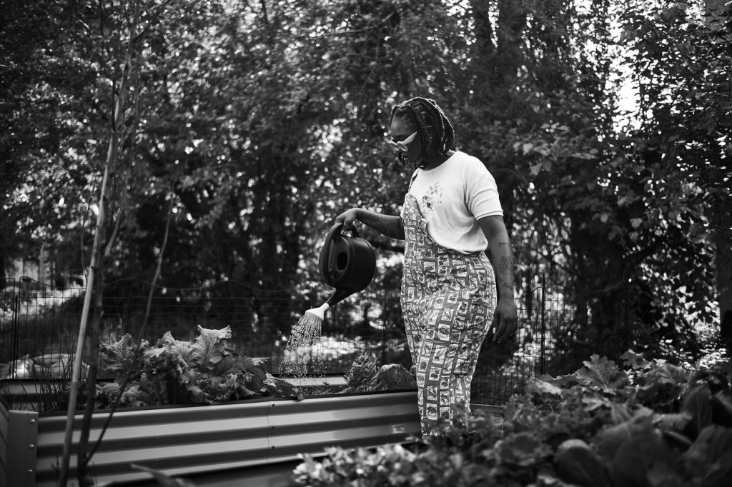 Saj Dillard waters plants at Sajeeda Urban Farm in Baltimore.