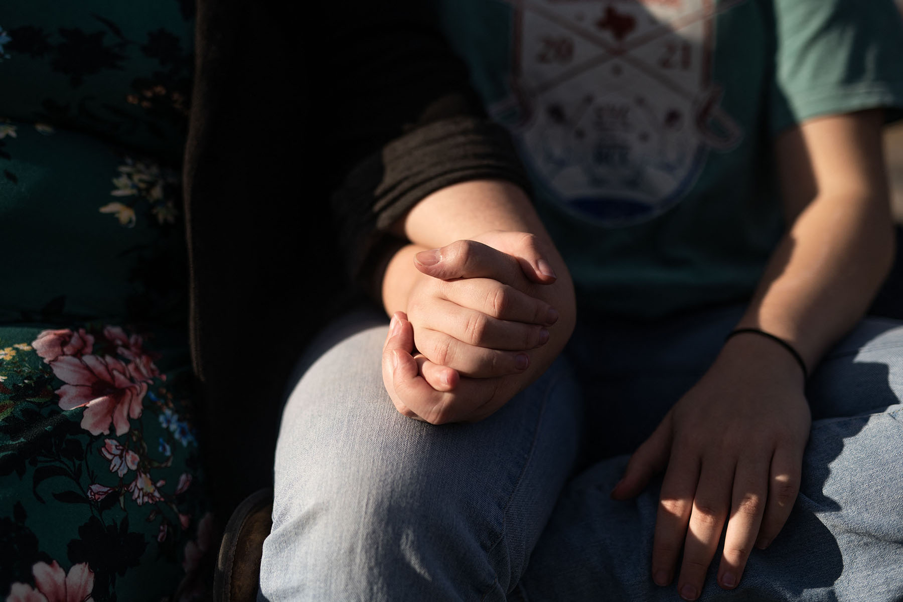 A mother holds her non-binary child's hand.