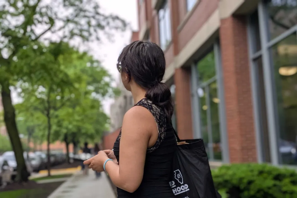Maya Roman waits on a sidewalk outside DePaul’s campus for a volunteer to pick up a bag of birth control supplies.