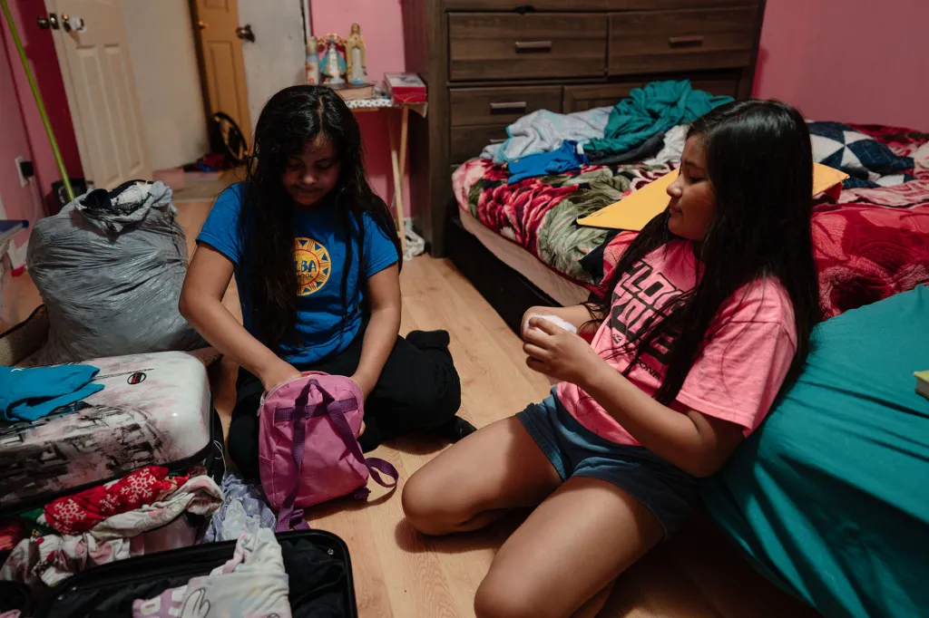 Ten-year-old twin sisters Paola and Elizabeth Guerra pack their suitcases in their bedroom.