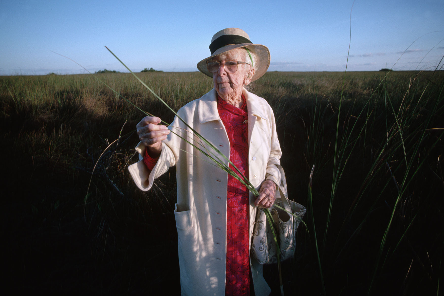 Marjory Stoneman Douglas, author and champion of the preservation of the Florida Everglades examines a grass stalk.
