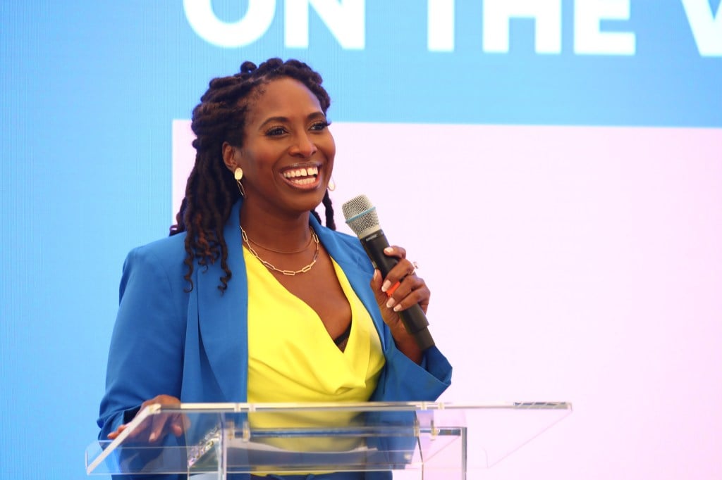 Eaddy at a podium, smiling, mic in hand.