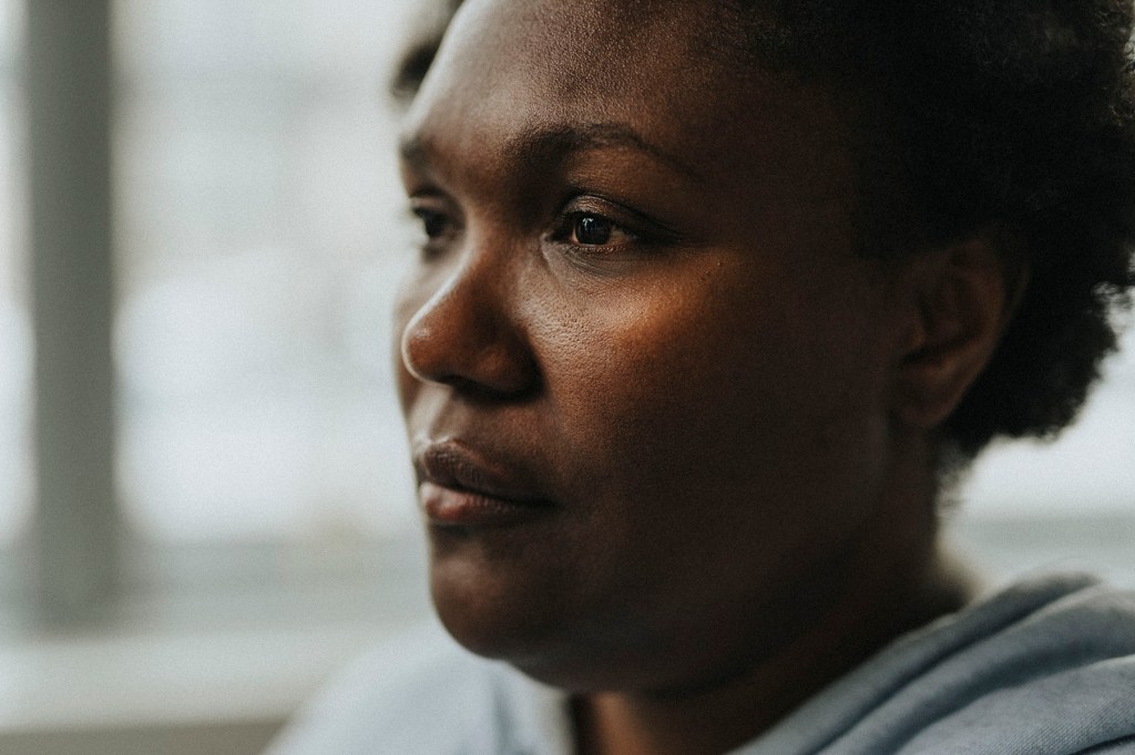A black woman stares into the distance with a strong expression on her face.