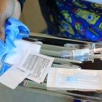 An immunization nurse carries a tray with a COVID-19 vaccine at Borinquen Health Care Center.