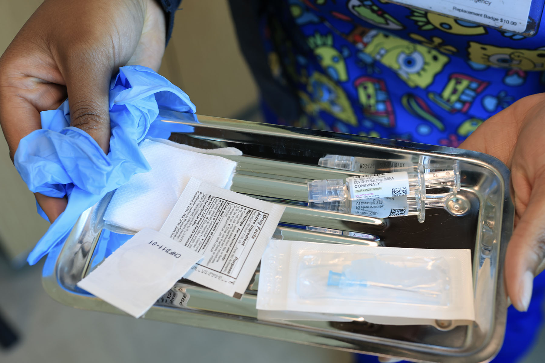 An immunization nurse carries a tray with a COVID-19 vaccine at Borinquen Health Care Center.