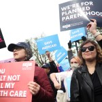 A group of protestors hold signs demanding access to reproductive healthcare and in support of Planned Parenthood.
