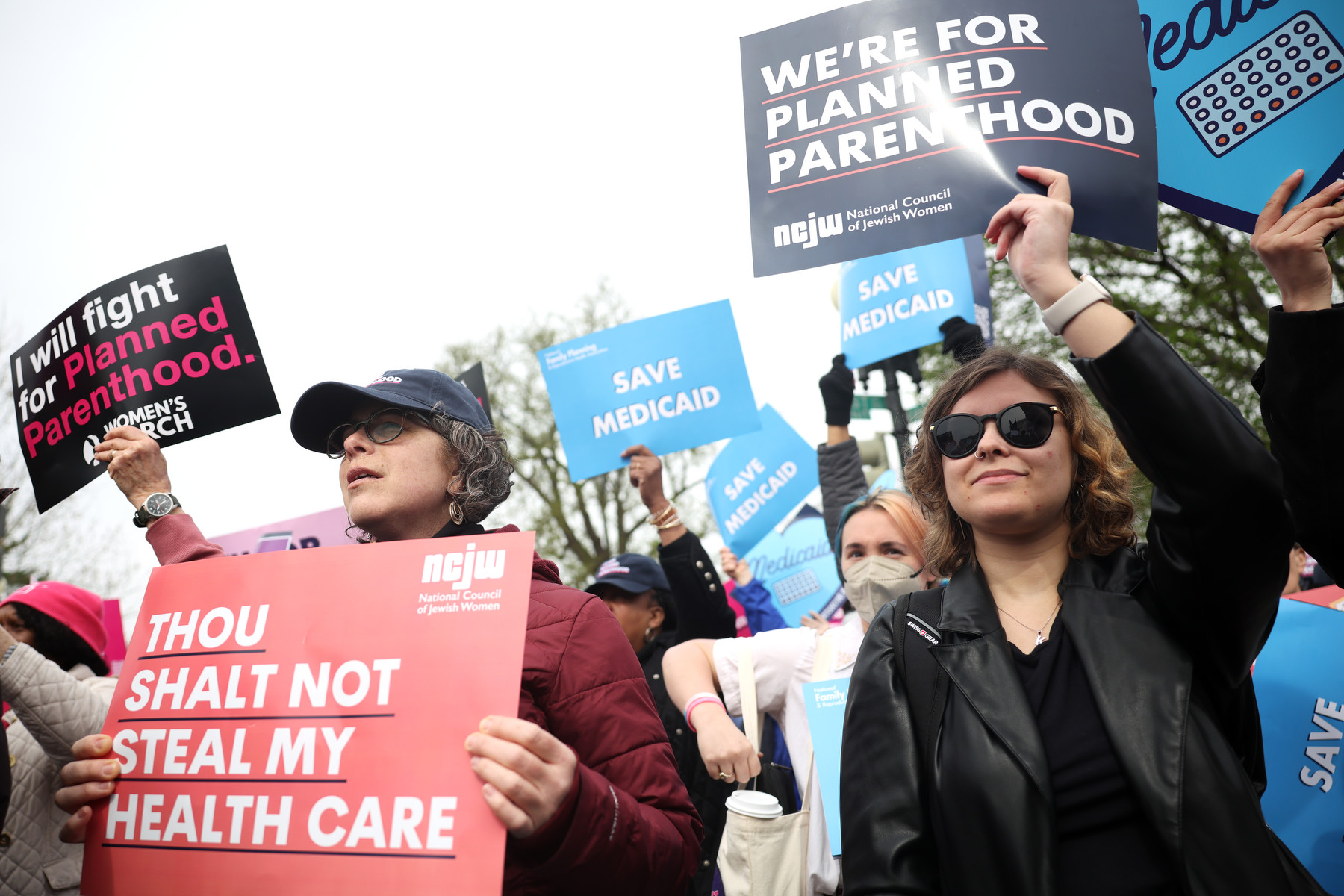 A group of protestors hold signs demanding access to reproductive healthcare and in support of Planned Parenthood.