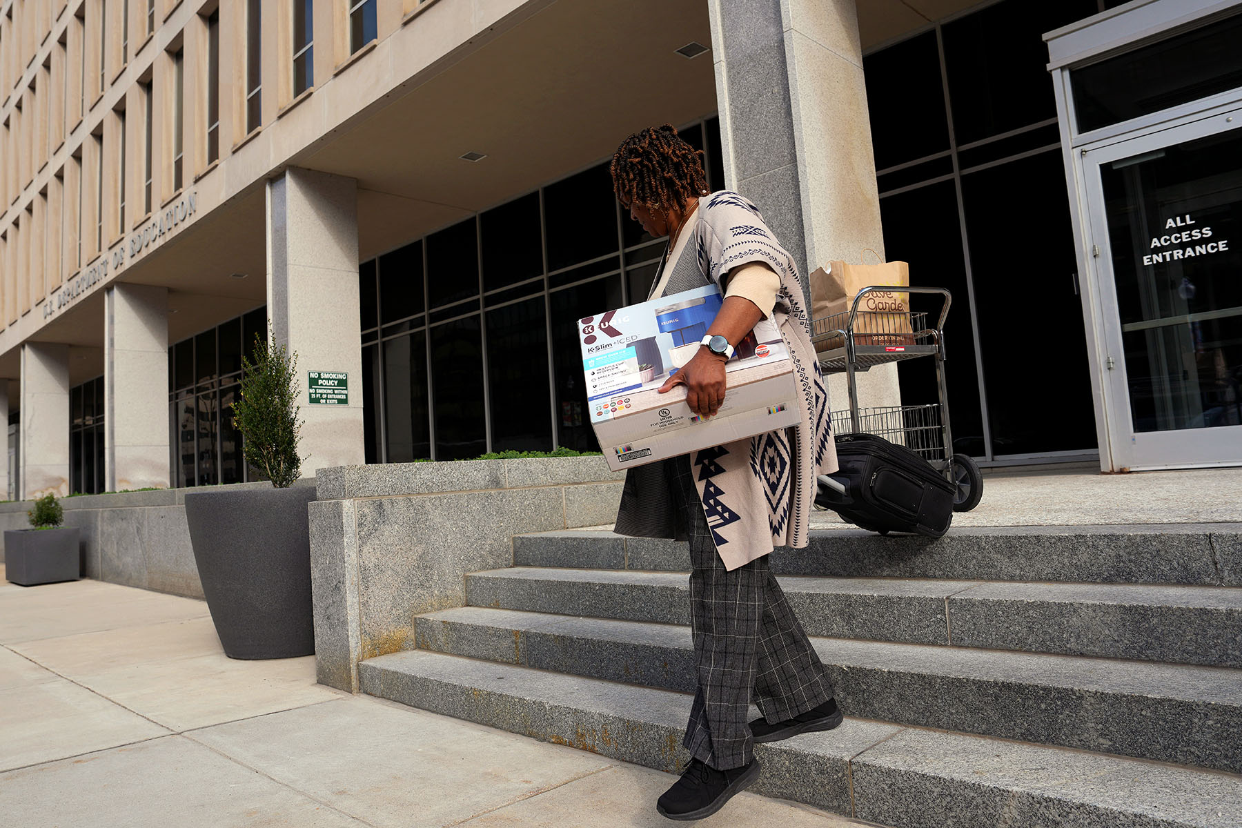 A Department of Education employee leaves the building with their belongings.