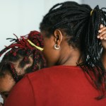 An unidentifiable mother holds her daughter tightly in her arms.