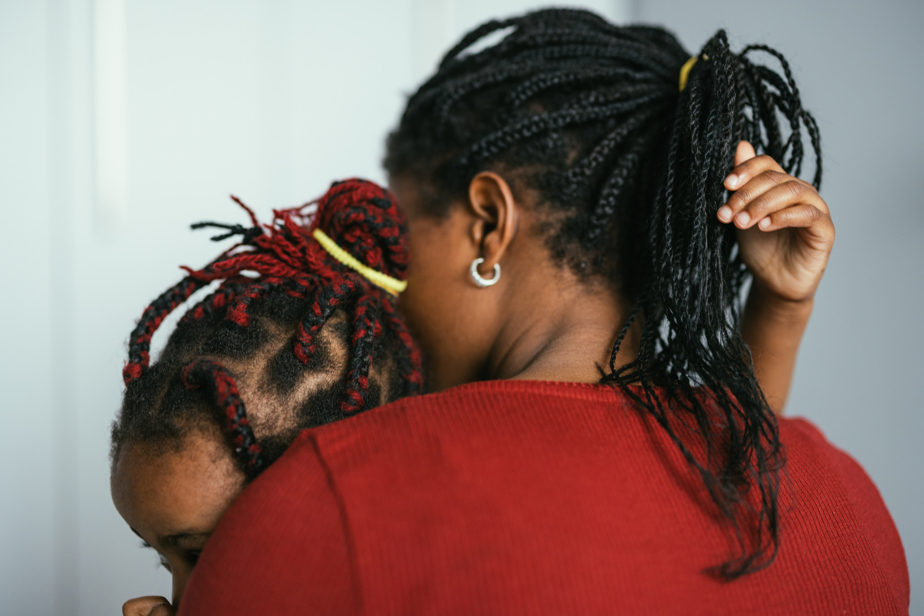 An unidentifiable mother holds her daughter tightly in her arms.