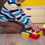 A young child plays with blocks on the floor.