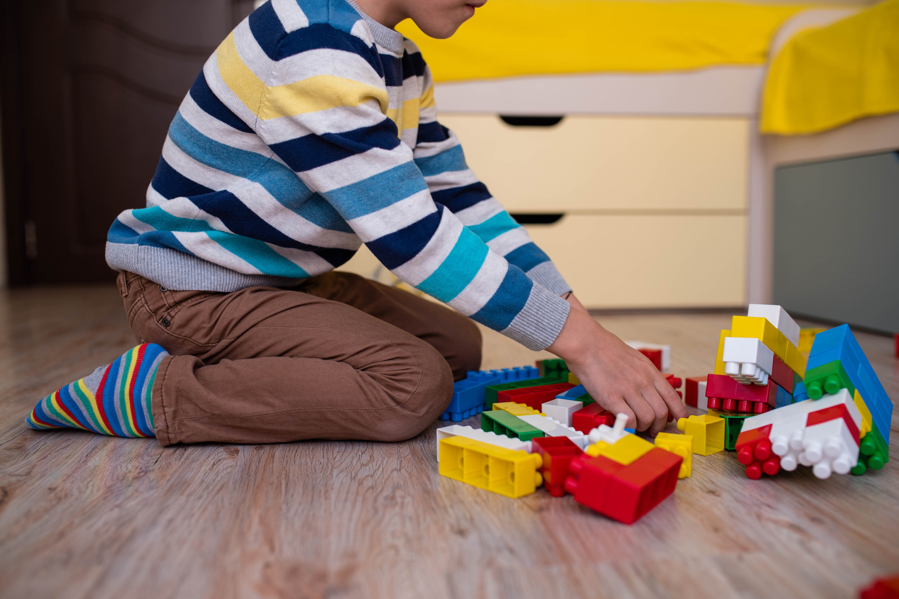 A young child plays with blocks on the floor.