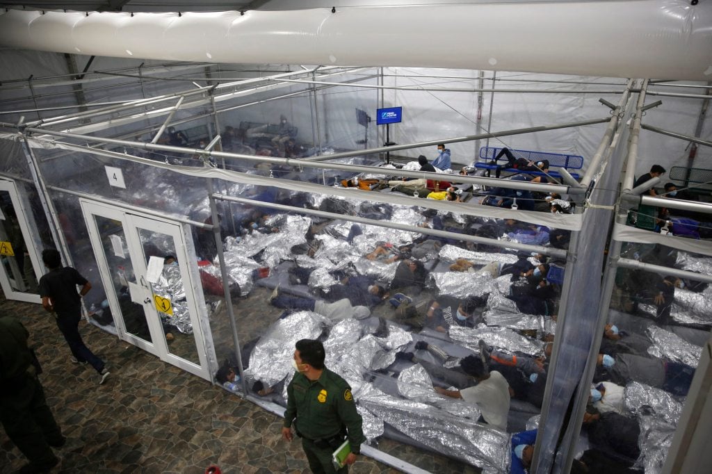 Children lay on the floor with mylar blankets in a holding cell.