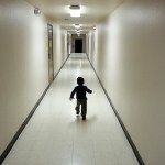 A toddler runs down a stark hallway.