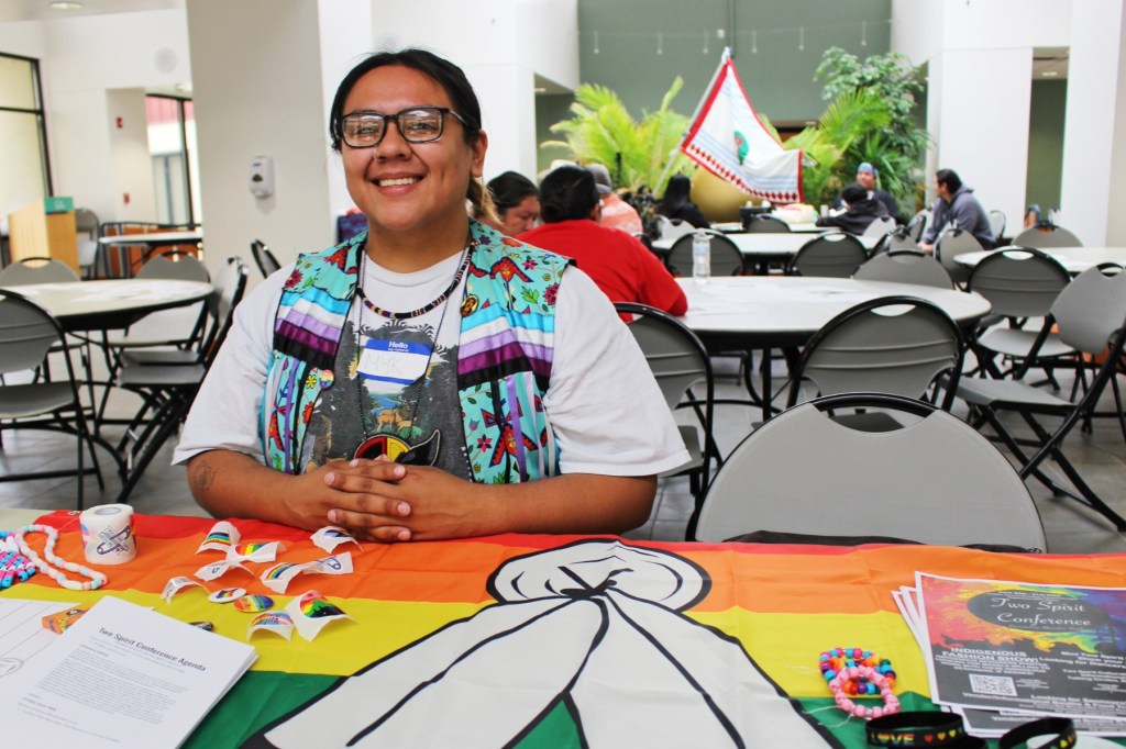 A person sits at a table at the Two Spirit Conference.