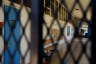 An empty school hallway is seen through a fence.
