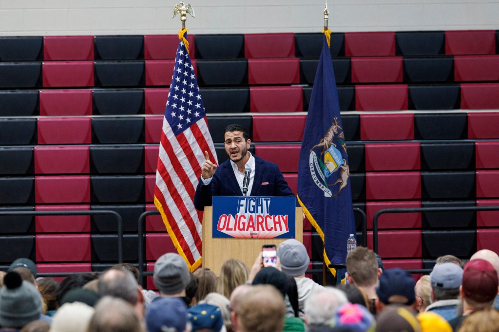A politician points from a podium that says “fight oligarchy”