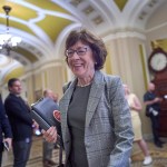 Sen. Susan Collins in a hallway surrounded by other people.