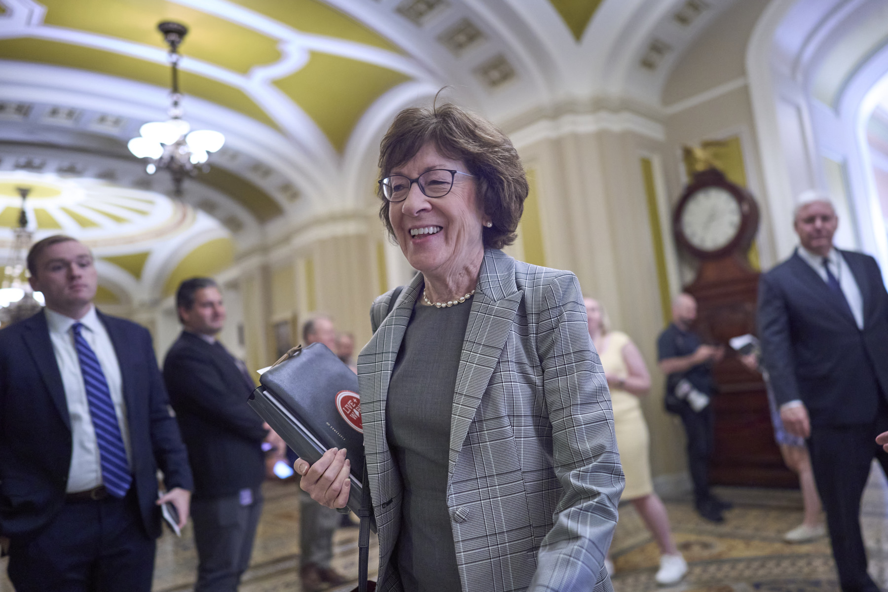 Sen. Susan Collins in a hallway surrounded by other people.