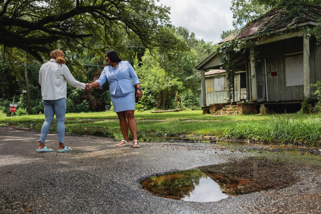 Carletta Davis speaks to a resident about a concerning leak in Downtown Prichard, Alabama.