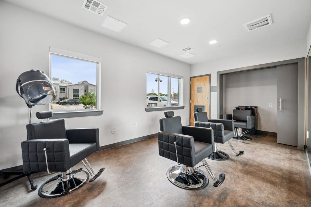 A bright salon space with black chairs and hair dryers at One Safe Place in Houston.