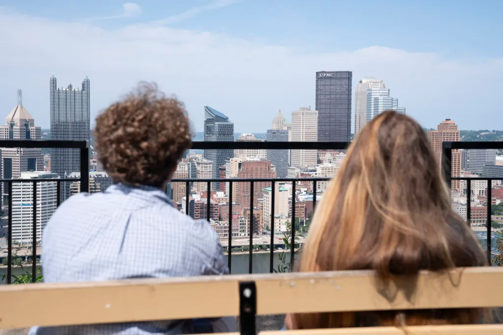 Lee and Nicole look out toward the Pittsburgh skyline from a bench.