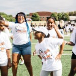 Five young girls play together on a field.