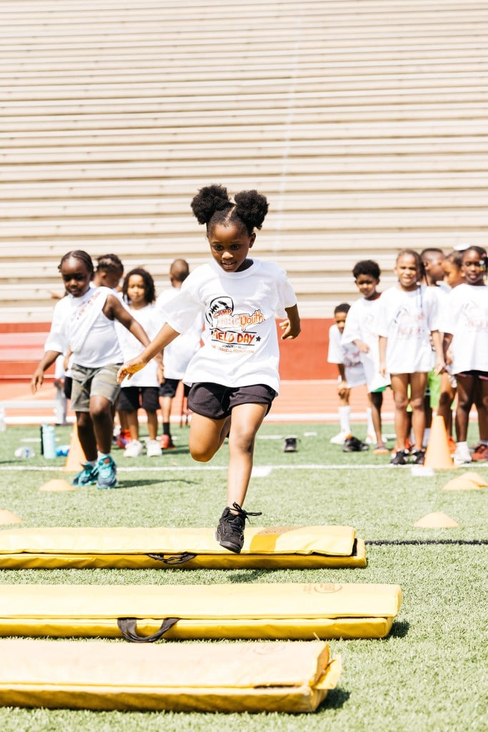 Children play athletic games together on a field.