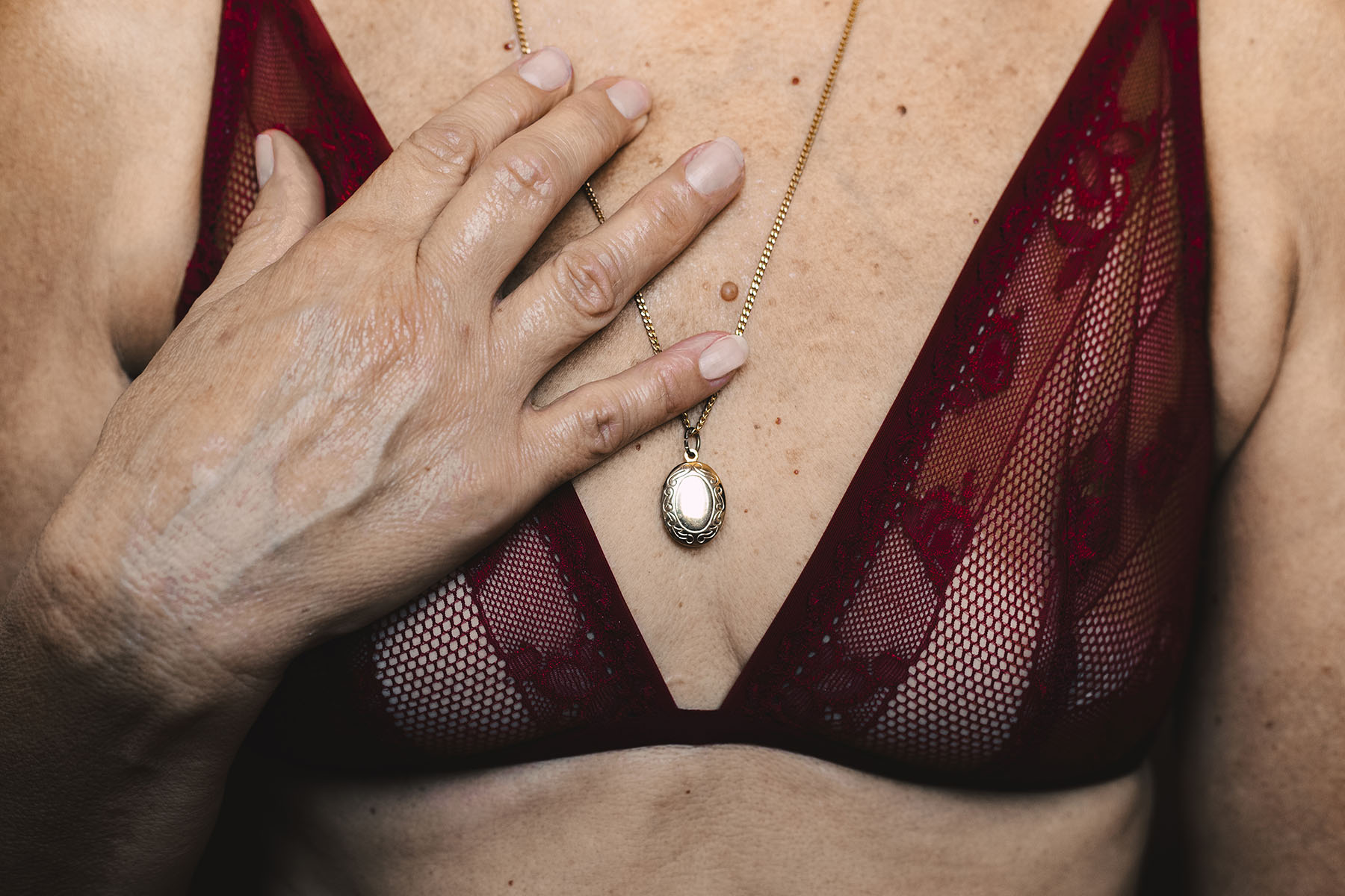 Close-up of a senior woman wearing a bra and a necklace.