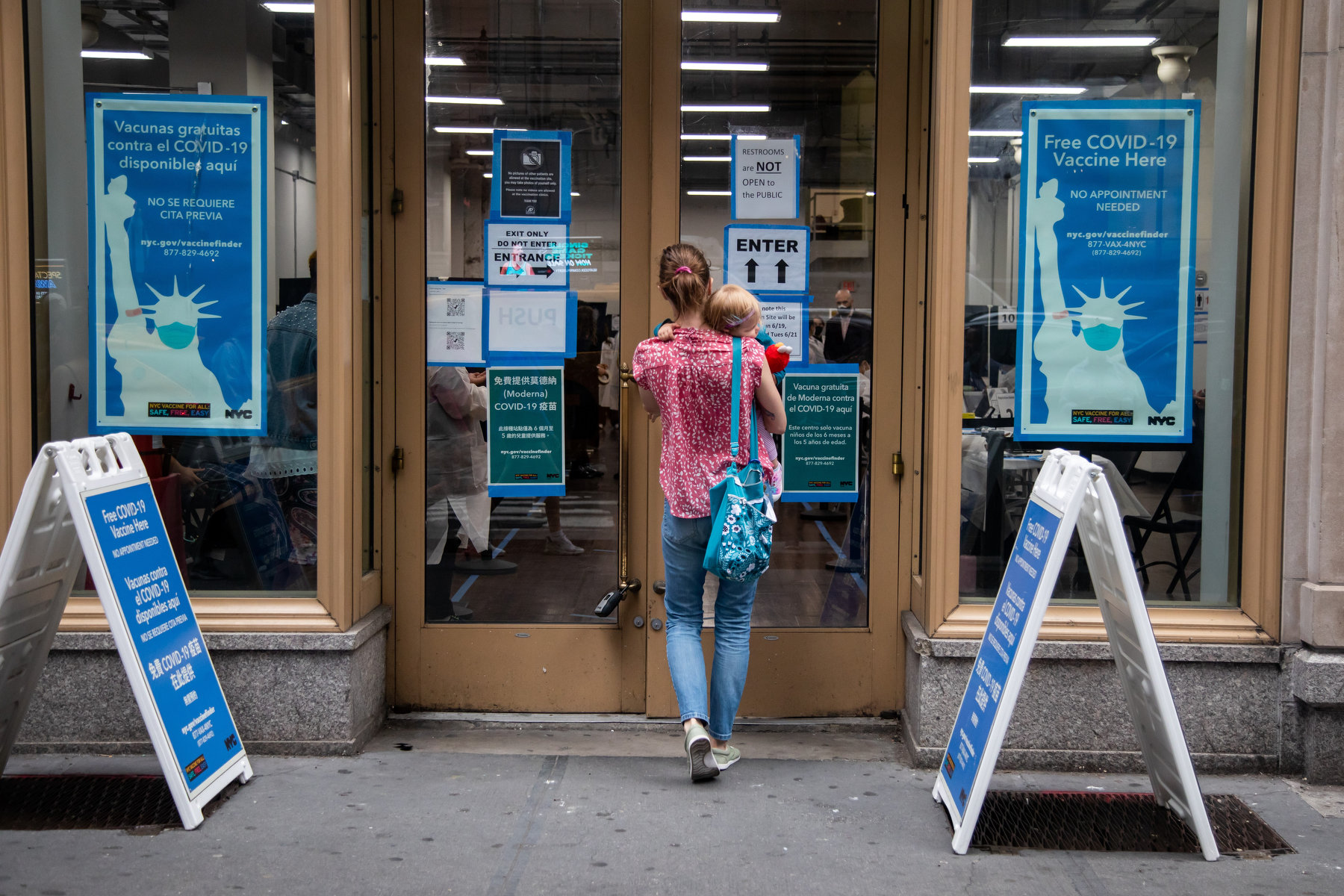 A woman holding an infant walks into a COVID vaccine clinic.
