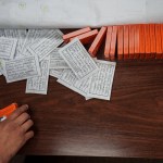 A hand reaches into frame on a table with several boxes and papers with medical instructions.