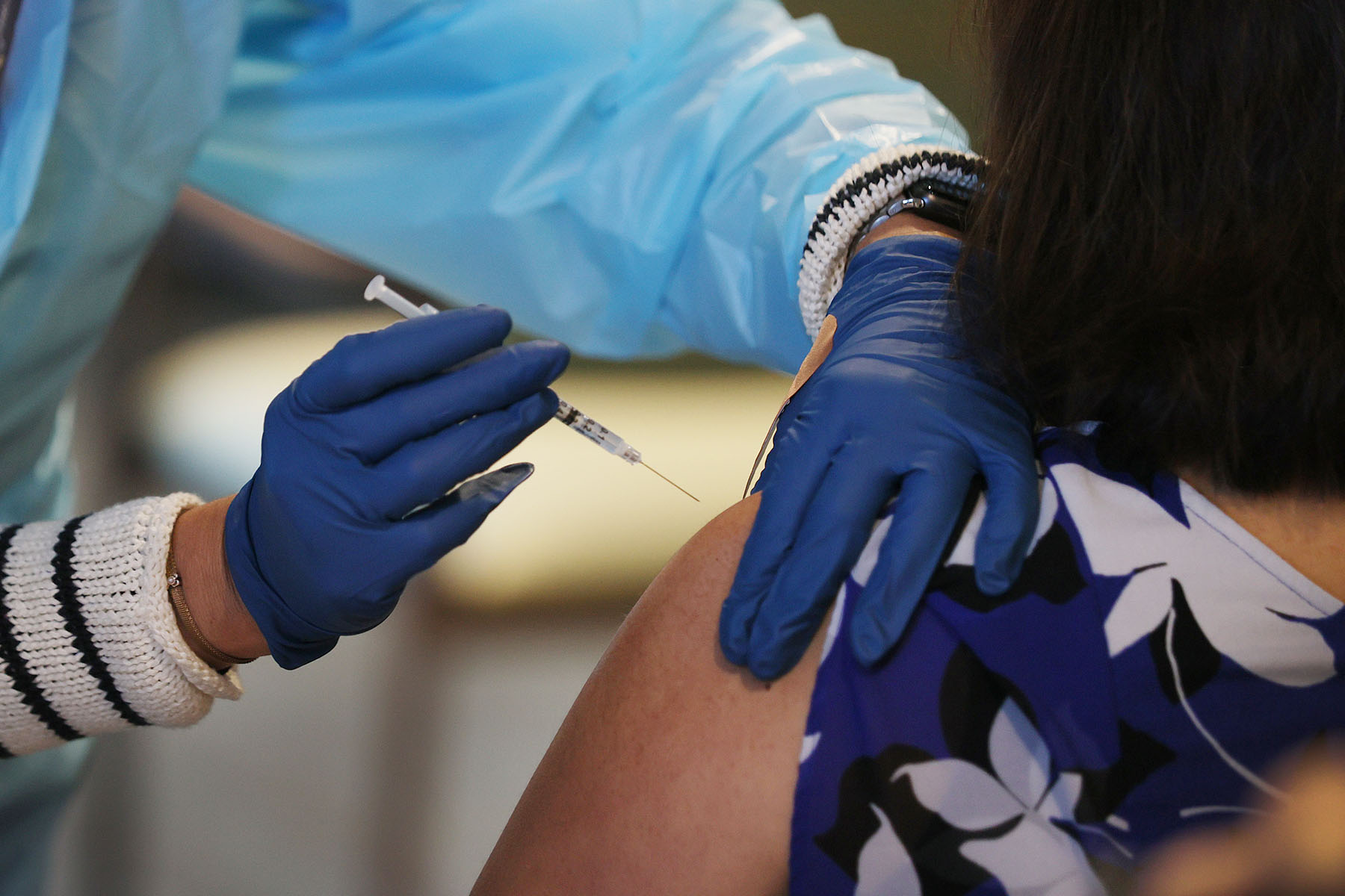 A healthcare worker administers a COVID-19 vaccine to a woman.