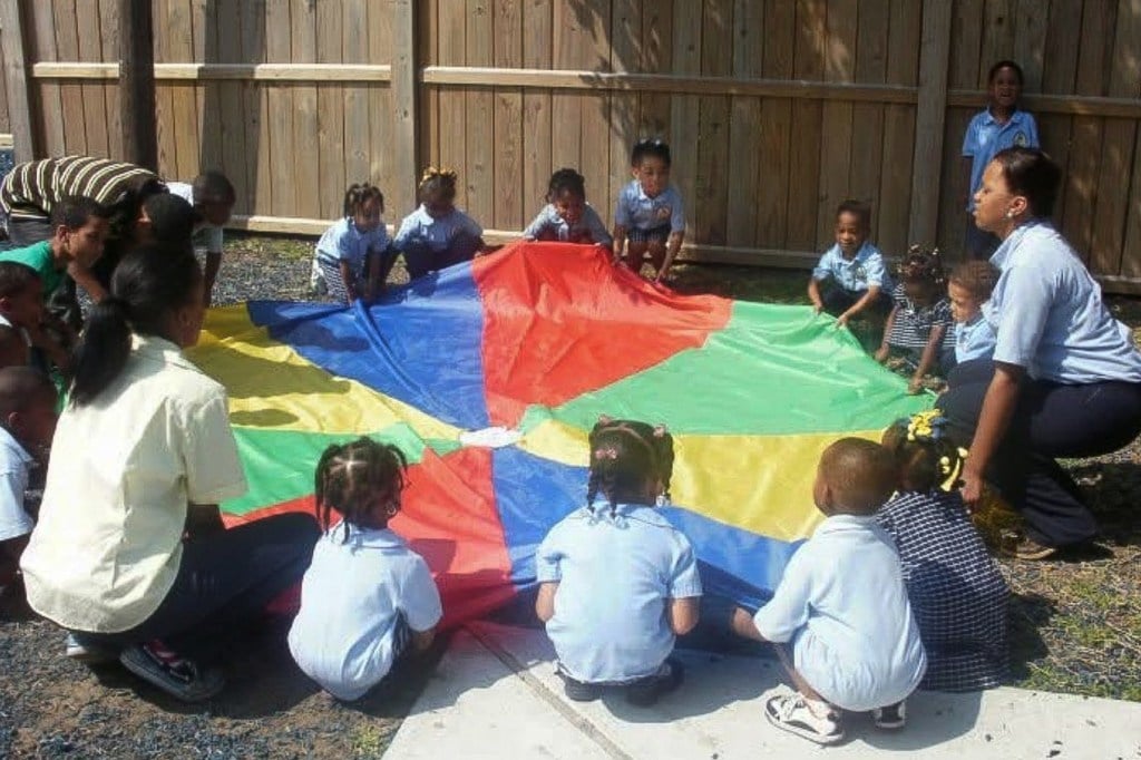 A group of children play outside with caregivers.