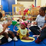 Two care providers hold infants in a daycare center.