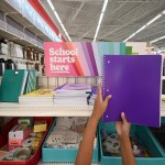 A child holds up a purple school notebook in a store.