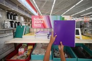 A child holds up a purple school notebook in a store.
