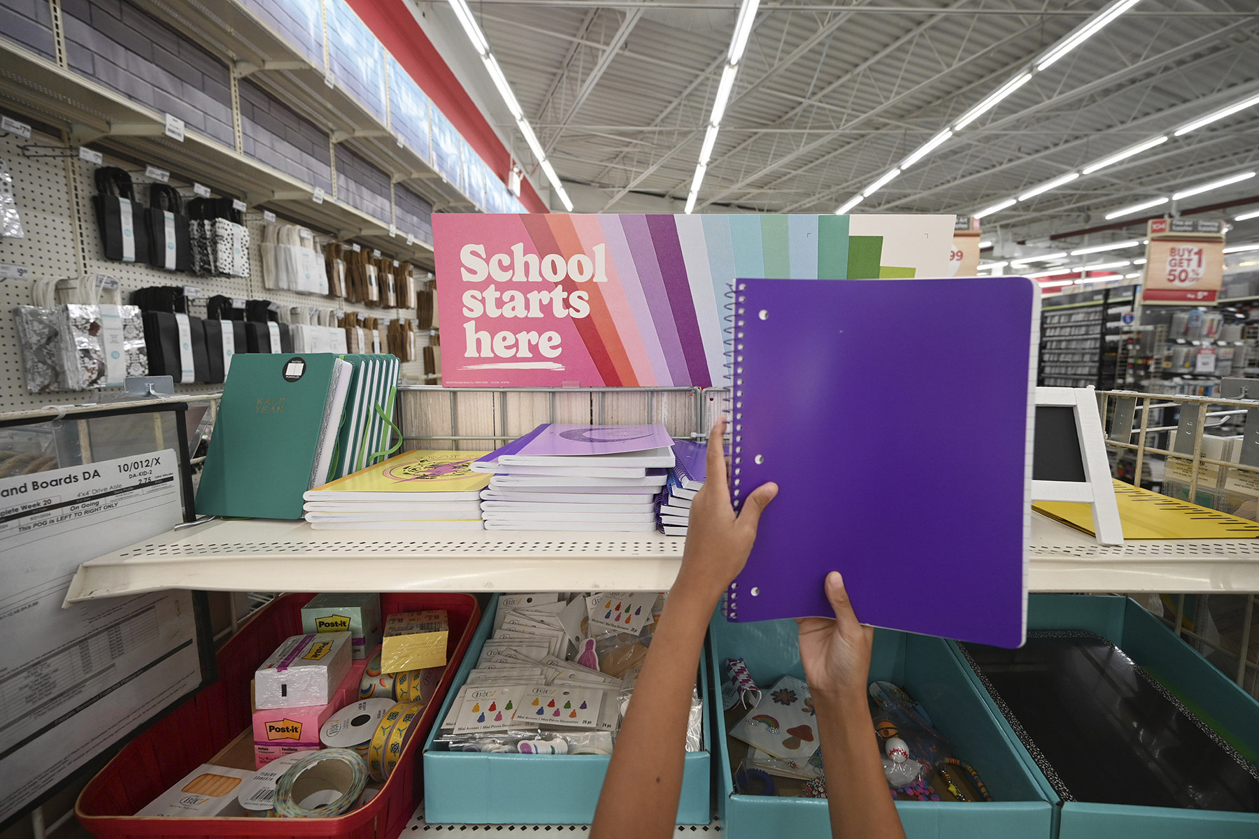 A child holds up a purple school notebook in a store.