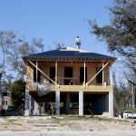 Construction workers stand on the roof of a house under construction.
