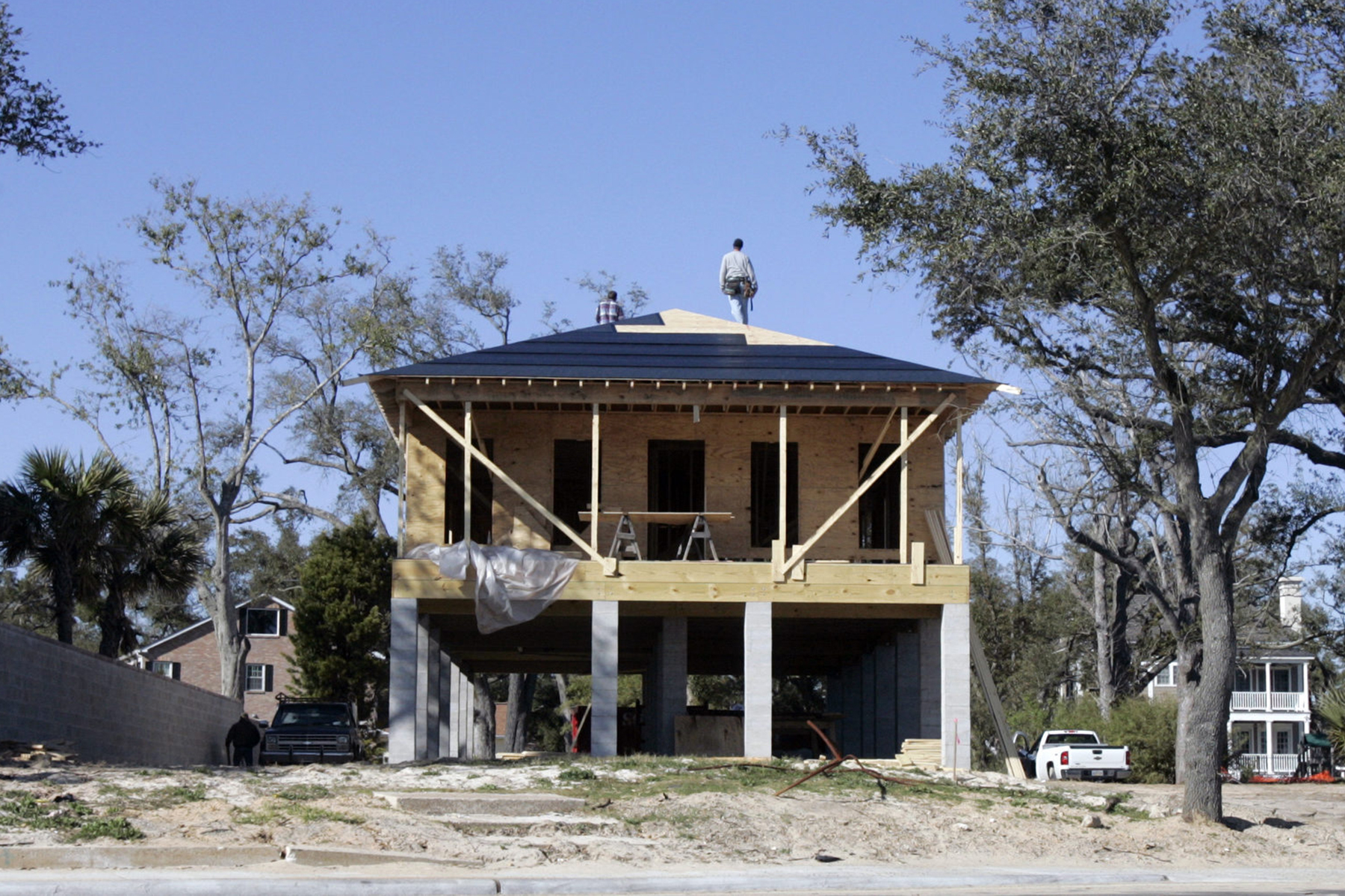 Construction workers stand on the roof of a house under construction.