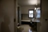 A shadow is cast on the wall outside an empty prison cell