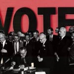 President Lyndon B. Johnson signs the Voting Rights Act of 1965 surrounded by civil rights leaders, including Martin Luther King Jr., with the word 
