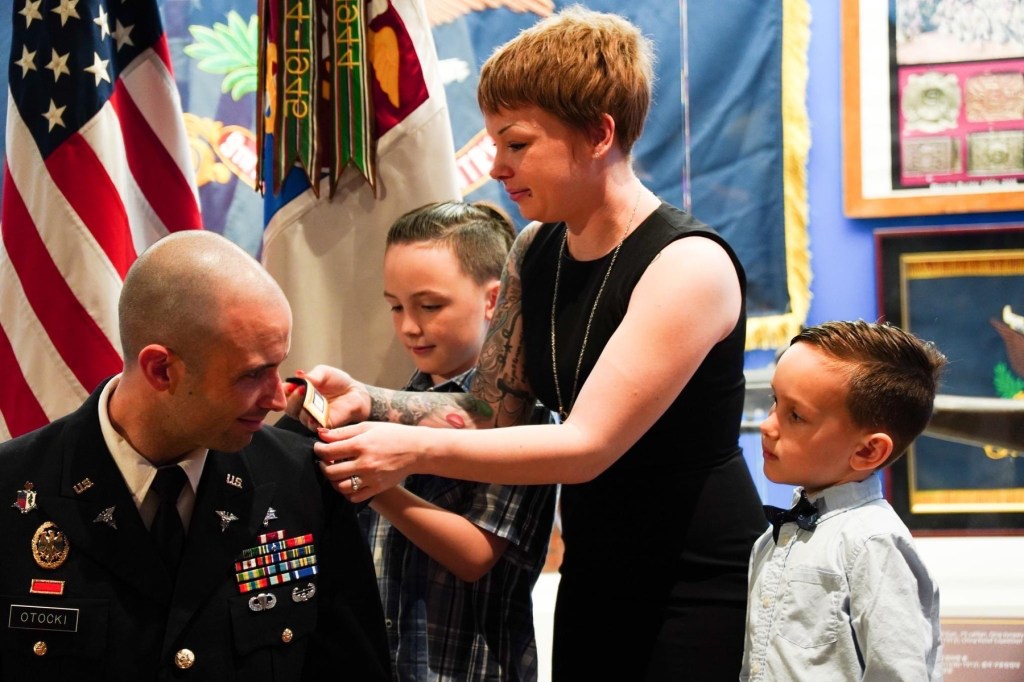 A family stands with a man in military uniform.