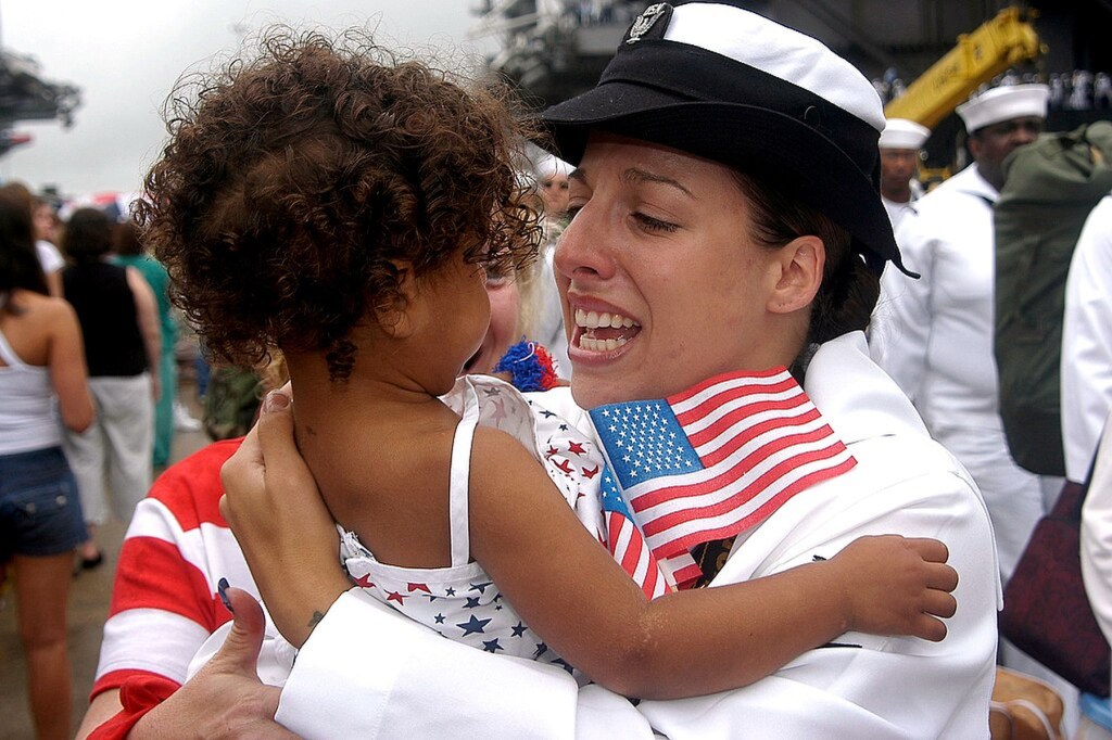 Leah Stiles hugs a toddler while in her Navy uniform.