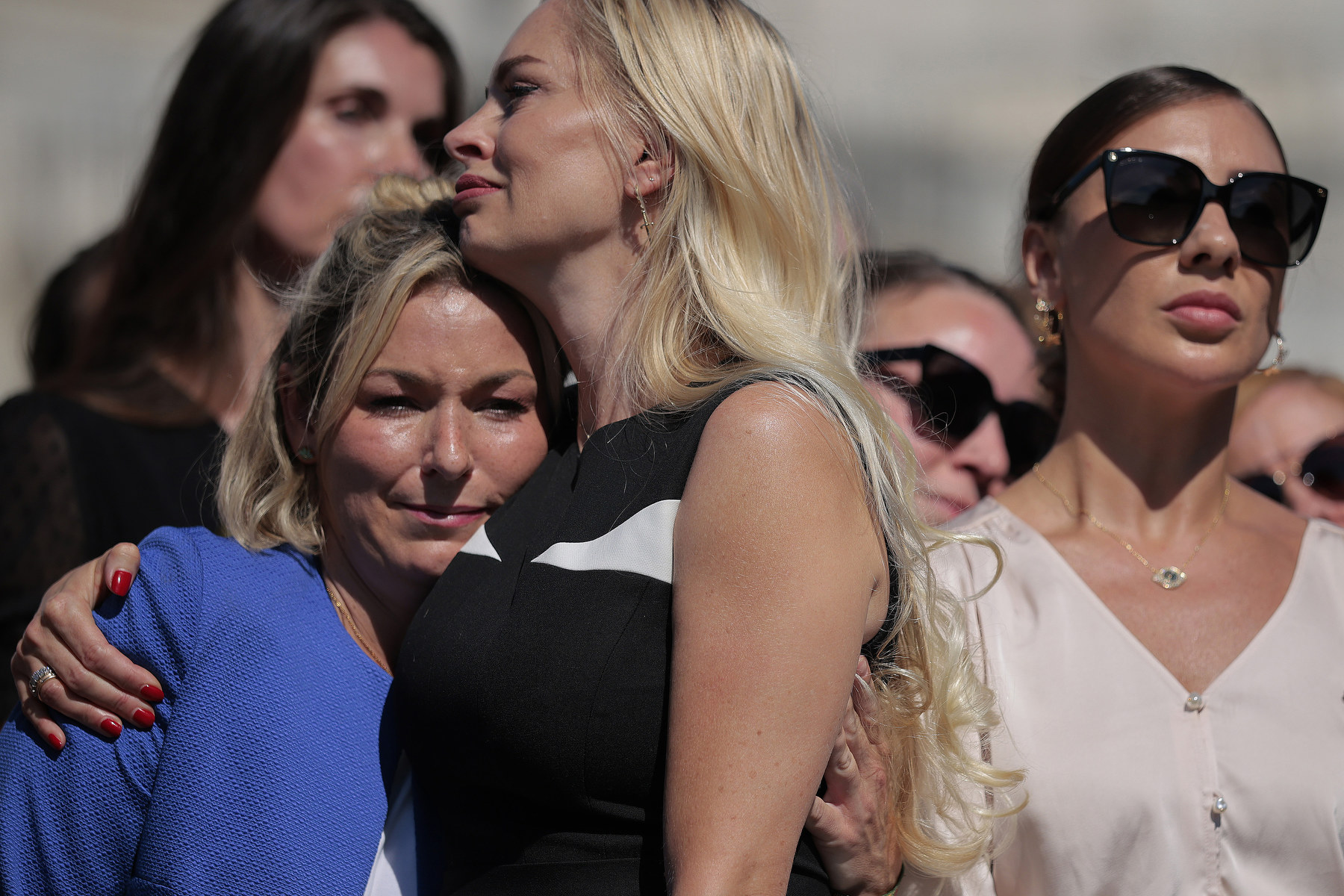 Two women embrace in a crowd of women.