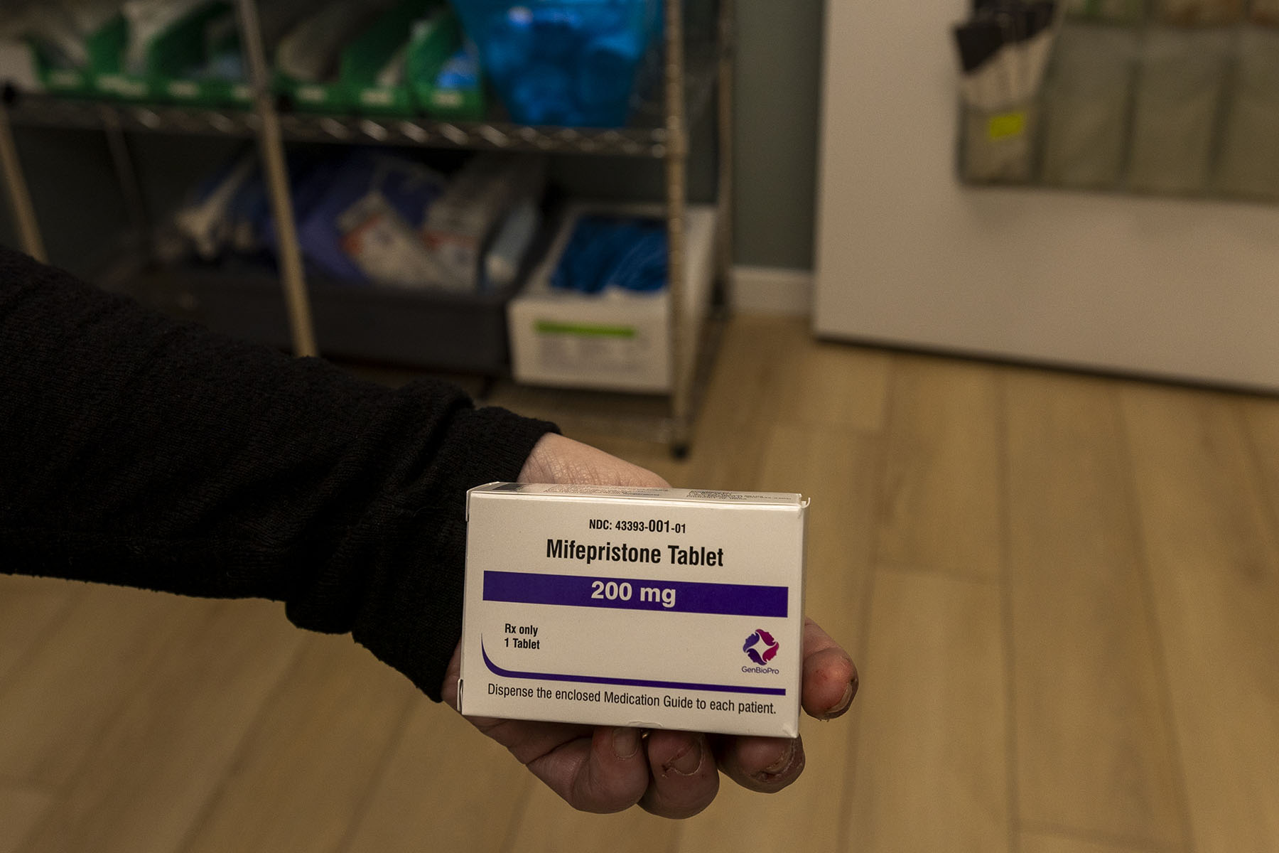 A person holds a packet of Mifepristone inside a clinic.