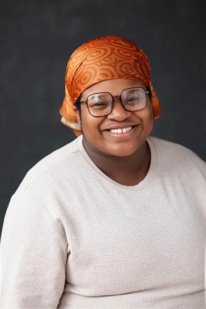 A portrait of Lotus Lloyd smiling into the camera.