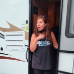 A woman stands in the doorway of an RV.