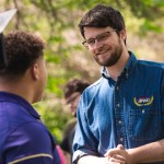 Will Lawrence smiles while speaking with a constituent outdoors.